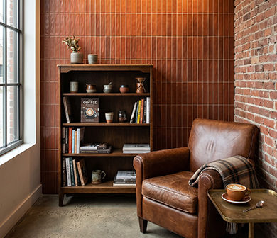 ShuangOu terracotta strip tile feature wall in a cozy reading corner with a leather armchair and bookshelf